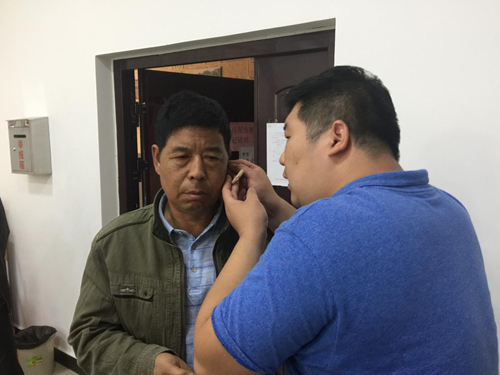 图为志愿者为残疾人安适配助听器 图为志愿者为残疾人安适配助听器