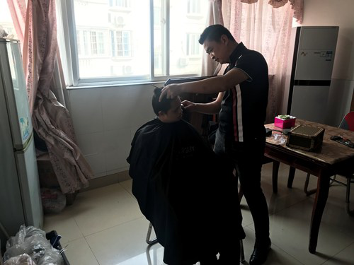 图为爱心企业代表为残疾人理发 图为爱心企业代表为残疾人理发