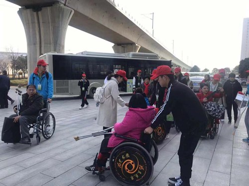 图为志愿者帮助残友乘车 图为志愿者帮助残友乘车